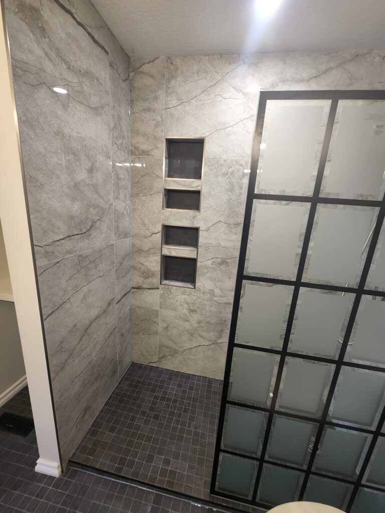 Modern shower area with marble walls and built-in shelves.
