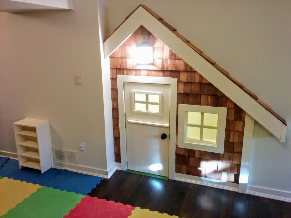 A small playhouse door and window built into a wall in a children's room.