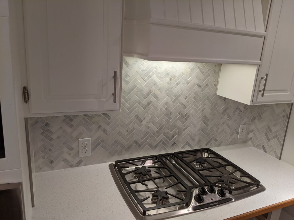 Modern kitchen with gas stove and backsplash.