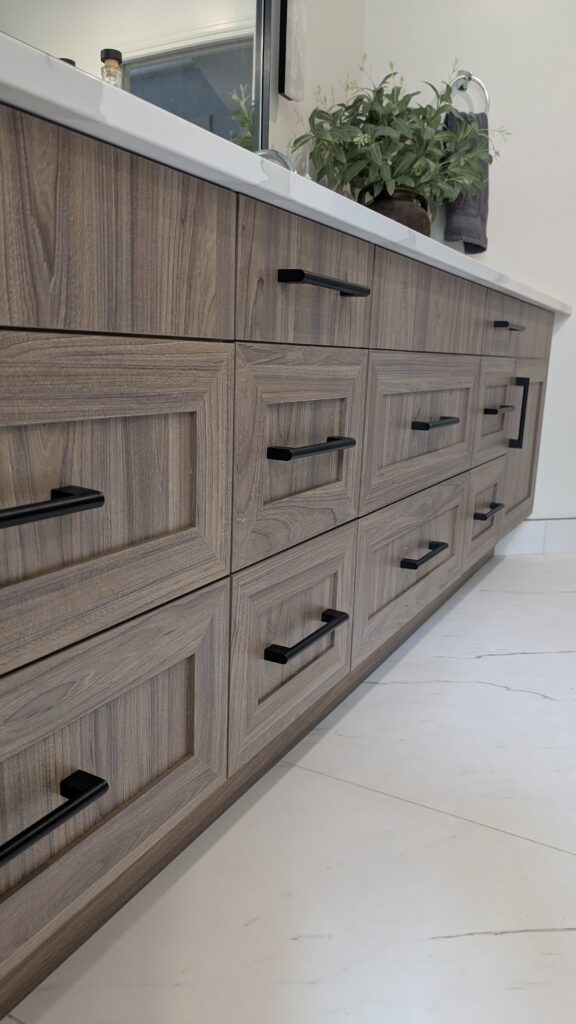 Wooden cabinets with black handles and plants.